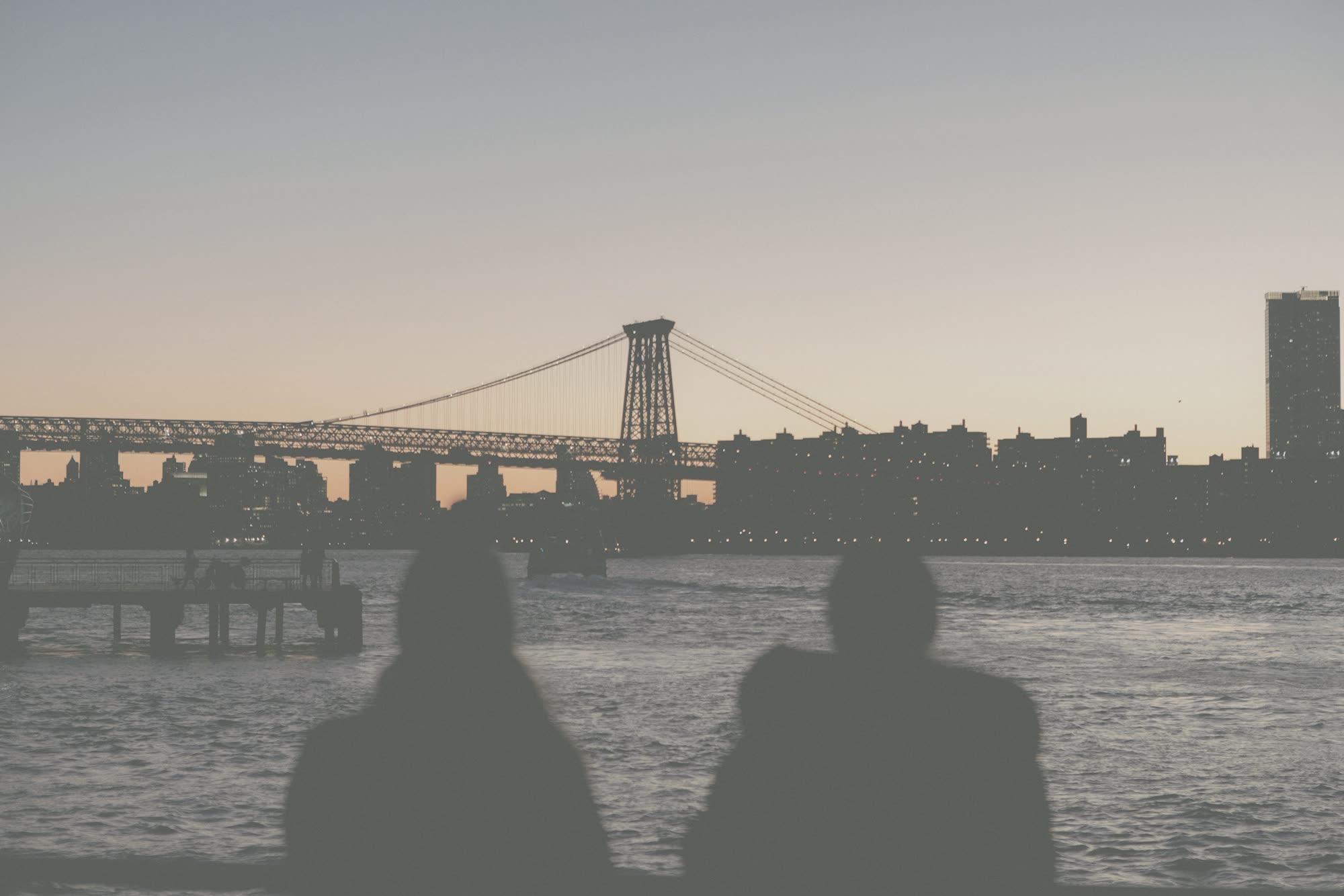 Two people on a pier at dusk, in flat, ungraded log.